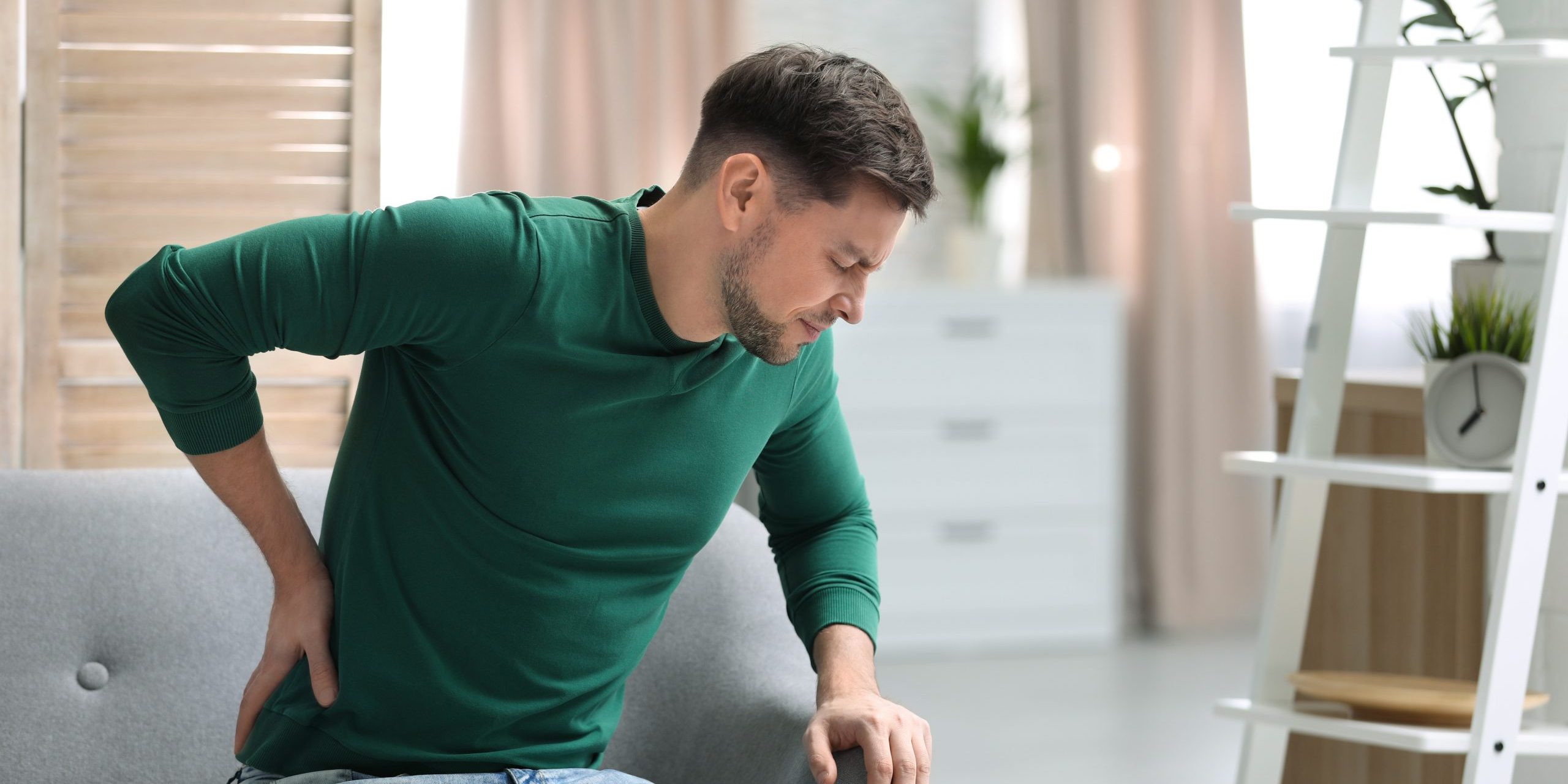 Young man suffering from back pain at home