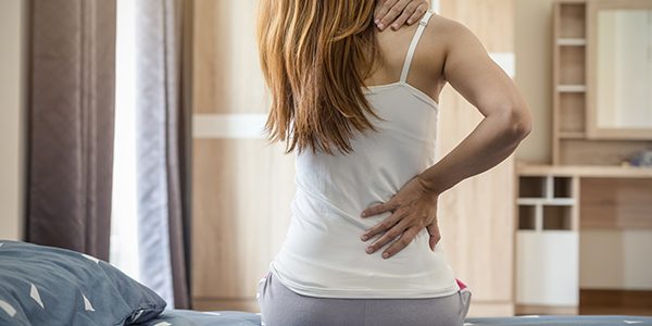 Woman suffering from back ache on the bed