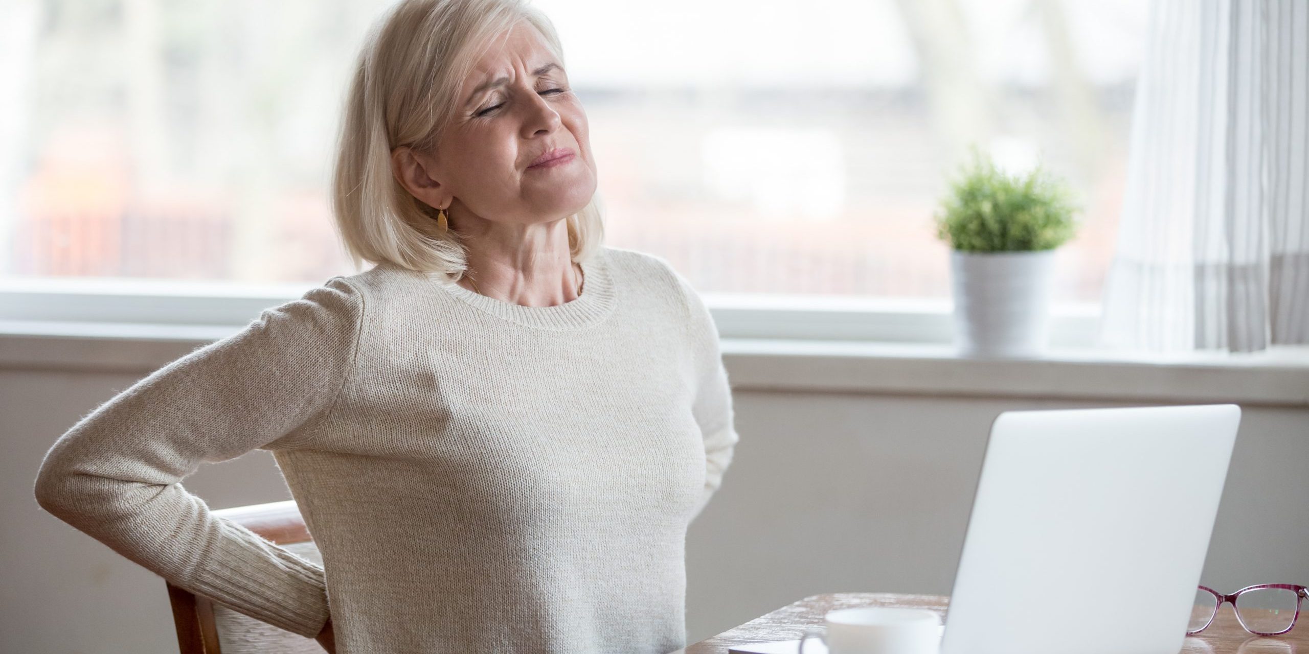 Upset mature woman sitting feeling back pain massaging aching mu