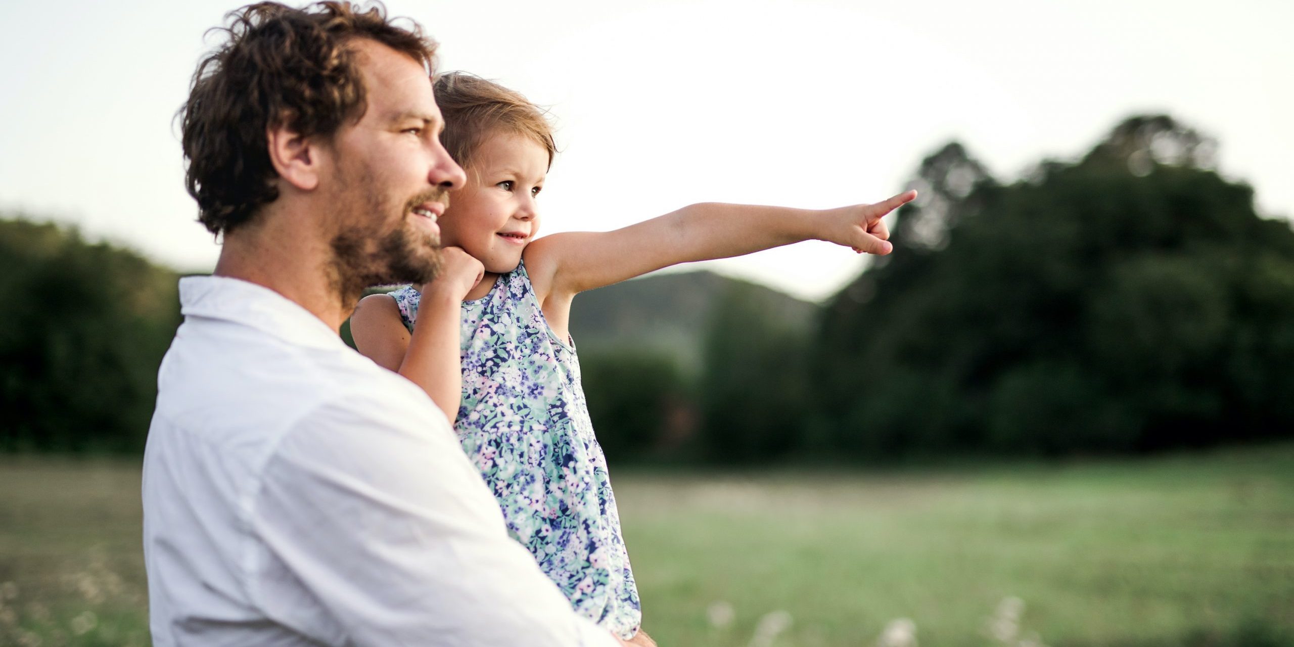 Young father in nature holding small daughter in the arms. Copy space.